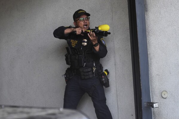 A Department of Homeland Security officer reacts after shooting pepper balls during a protest at the U.S. Department of Justice Federal Bureau of Prisons after federal immigration authorities conducted an operation on Friday, June 6, 2025, in Los Angeles. (AP Photo/Jae C. Hong)
