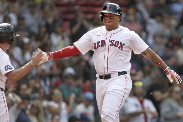 Boston Red Sox's Rafael Devers, right, is all smiles as he heads to the dugout after after hitting a home run during the seventh inning of a baseball game against the Texas Rangers, Thursday, May 8, 2025, in Boston. (AP Photo/Jim Davis)