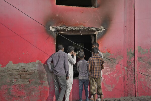 Youngsters look at a church vandalized by angry Muslim mob in Jaranwala near Faisalabad, Pakistan, Thursday, Aug. 17, 2023. Muslims in eastern Pakistan went on a rampage Wednesday over allegations that a Christian man had desecrated the Quran, demolishing the man's house, burning churches and damaging several other homes, police and local Christians said. There were no immediate reports of casualties. (AP Photo/K.M. Chaudary)