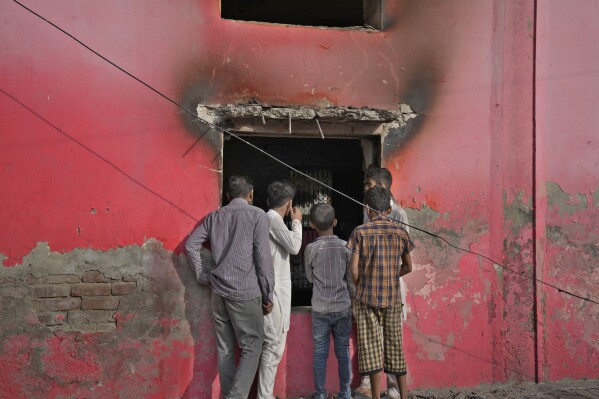 Jóvenes observan una iglesia destrozada por una turba musulmana enojada en Jaranwala, cerca de Faisalabad, Pakistán, el jueves 17 de agosto de 2023. Los musulmanes en el este de Pakistán se enfurecieron el miércoles por las acusaciones de que un hombre cristiano había profanado el Corán, demoliendo la casa del hombre, quemando iglesias y dañando varias otras casas, dijeron la policía y los cristianos locales.  No hubo informes inmediatos de víctimas.  (Foto AP/KM Chaudary)