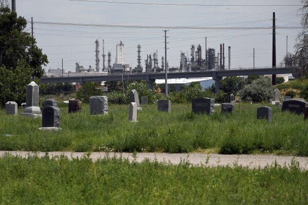 Riverside Cemetery is seen in front of an oil refinery in Commerce City, Colo., on Tuesday, July 25, 2023. Residents in the area say fumes from the refinery and the lack of trees make their neighborhood hotter. As climate change fans hotter and longer heat waves, breaking record temperatures across the U.S. and leaving dozens dead, the poorest Americans suffer the hottest days with the fewest defenses. Air conditioning, once a luxury, is now a matter of survival. (AP Photo/Thomas Peipert)
