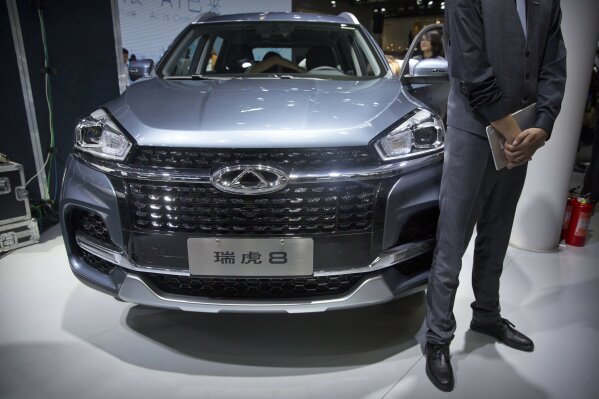FILE - In this April 25, 2018, file photo a staff member stands next to a Tiggo 8 SUV by Chinese automaker Chery after a press conference at the China Auto Show in Beijing. A California company says it will build and sell Chinese-designed automobiles in the U.S. at the end of next year or early in 2022. HAAH Automotive Holdings says it has an agreement with large Chinese automaker Chery Automobile to provide the vehicles, which will be assembled in a U.S. factory. HAAH says the first vehicle sold will be a midsize SUV. (AP Photo/Mark Schiefelbein, File)