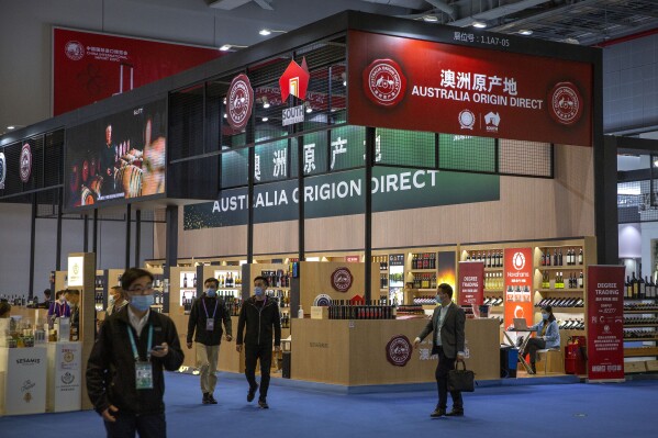 FILE - Visitors wearing face masks walk past a display of Australian wines and other agricultural products at the China International Import Expo (CIIE) in Shanghai, China, Nov. 5, 2020. China on Thursday, March 28, 2024, said it would lift tariffs placed on Australian wine over three years ago, in a sign of improving ties between Australia and China.(AP Photo/Mark Schiefelbein, File)
