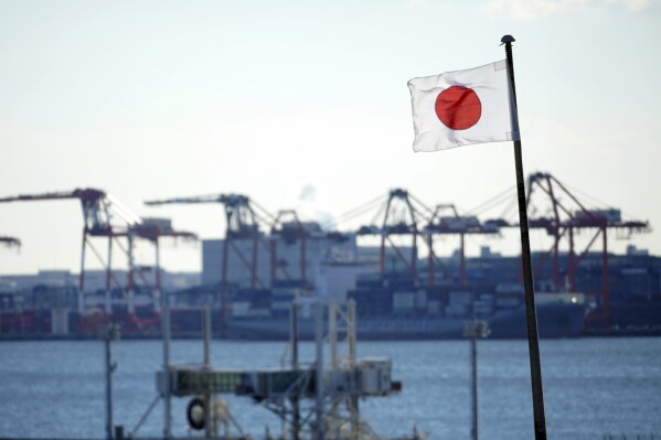 FILE - A national flag flies near a container port in Tokyo, on Jan. 20, 2022. Japan’s trade deficit in April grew nearly 8% from a year earlier as the weak yen boosted the value of imports, offsetting gains from a jump in exports, government data showed Wednesday, May 22, 2024. (AP Photo/Eugene Hoshiko, File)