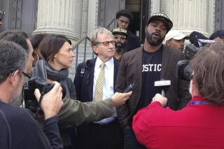 FILE - In this Jan. 26, 2017, file photo, Robert Jones, right, speaks with reporters, with defense attorneys Emily Maw, left, and Barry Scheck, at the New Orleans courthouse. Local prosecutors have reached a $2 million settlement with the New Orleans man who spent 23 years in prison before being cleared on charges that included rape and manslaughter. District Attorney Jason Williams said he reached the settlement Tuesday, Aug. 17, 2021 with Robert Jones, who was formally cleared of the charges on his 44th birthday in 2017. (AP Photo/Kevin McGill, File)