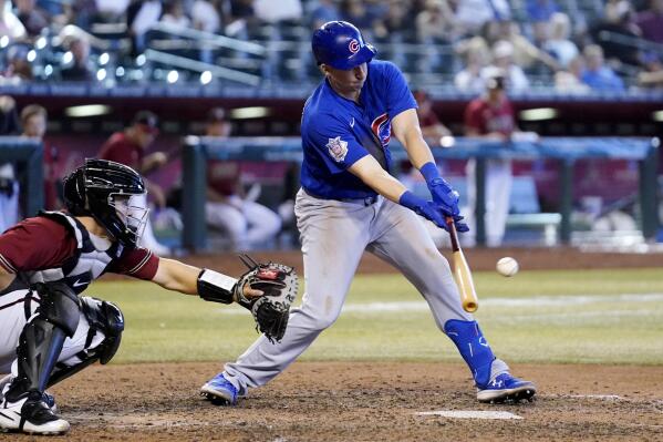 Chicago Cubs' Frank Schwindel, right, connects for a run-scoring single as Arizona Diamondbacks catcher Daulton Varsho reaches out with his glove during the ninth inning of a baseball game Sunday, May 15, 2022, in Phoenix. (AP Photo/Ross D. Franklin)