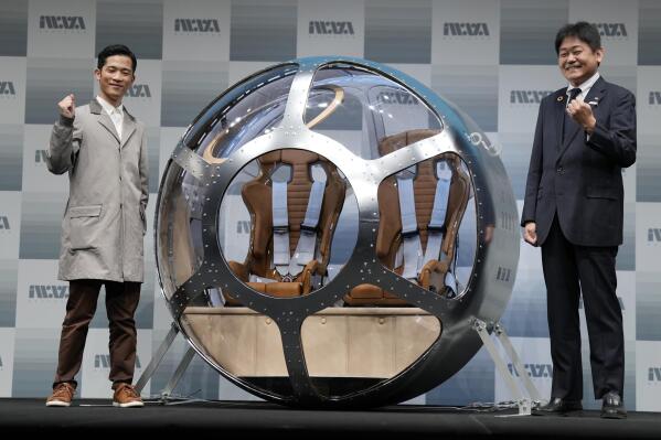 Keisuke Iwaya, left, CEO of a Japanese space development company, Iwaya Giken, and Takayuki Hanasaka, JTB Senior Managing Executive Officer, pose for a photo after unveiling a two-seater cabin and a balloon that the company says is capable of rising to an altitude of 15 miles, which is roughly the middle of the stratosphere, as he speaks during a news conference in Tokyo, Tuesday, Feb. 21, 2023. (AP Photo/Eugene Hoshiko)