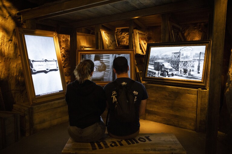 Visitors watch educational videos at the Monuments Men and Women exhibition, which features a recreation of the salt mine where Nazis hid artwork during World War II, at The National WWII Museum in New Orleans, Thursday, Feb. 15, 2024. (AP Photo/Christiana Botic)