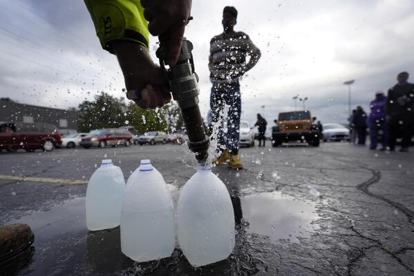 Kevin Stack with the Berrien County Road Department fills up jugs with non-potable water for Elliot Napier in the Benton Harbor High School parking lot Thursday, Oct. 21, 2021, in Benton Harbor, Mich. The water system in Benton Harbor has tested for elevated levels of lead for three consecutive years. In response, residents have been told to drink and cook with bottled water and the state has promised to spend millions replacing lead service lines. (AP Photo/Charles Rex Arbogast)