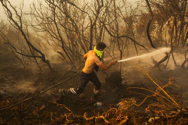 A Turkish firefighter works to extinguish a forest wildfire in Beykoz, outskirts Istanbul, Turkey, Wednesday, July 26, 2023. Water-dropping planes, helicopters and firefighters were also deployed to fight a blaze that broke out Wednesday at a forest near the district of Beykoz, in Istanbul, where temperatures reached 43 C. (AP Photo/Emrah Gurel)