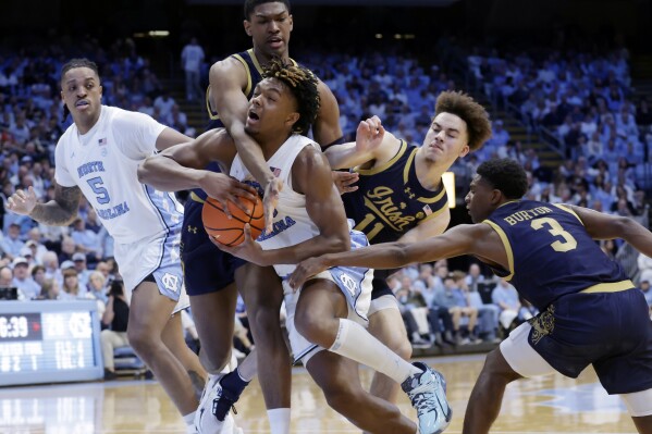 North Carolina forward Harrison Ingram, center, drives against Notre Dame forward Kebba Njie, top center, and guard Braeden Shrewsberry (11) and Markus Burton (3) during the first half of an NCAA college basketball game Tuesday, March. 5, 2024, in Chapel Hill, N.C. North Carolina forward Armando Bacot (5) looks on. (AP Photo/Chris Seward)
