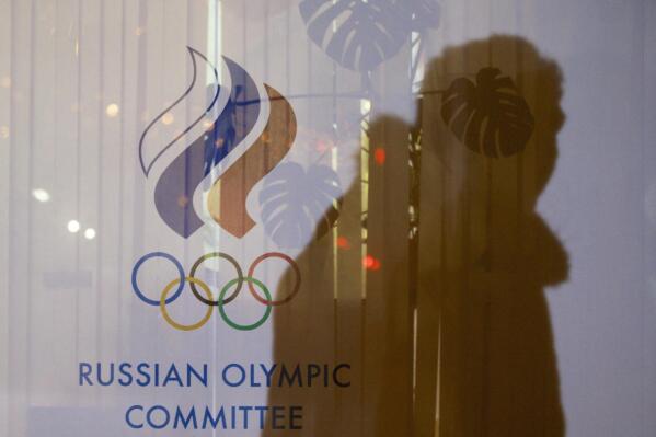 FILE - A man walking past the Russian Olympic Committee building casts a shadow on a window in Moscow, Russia on Nov. 18, 2015. The invasion of Ukraine could further undermine Russia's status as an elite sports dynasty, which already has been weakened by deception and doping scandals but often punished only by a tepid pushback from international sports bodies. (AP Photo/Pavel Golovkin, File)