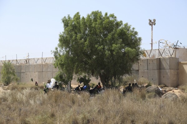 FILE - Migrants gather in a desert area on the Libyan side of the Tunisia-Libya border on Sunday July 23, 2023. Libyan authorities said on Wednesday, Aug, 9 at least 27 suspected African migrants have died in the country’s western desert near the border with Tunisia. In a statement posted on Facebook, Libya’s Interior Ministry said the bodies were discovered recently near the border and that a forensic team had been deployed to the area. (AP Photo/Yousef Murad, file)