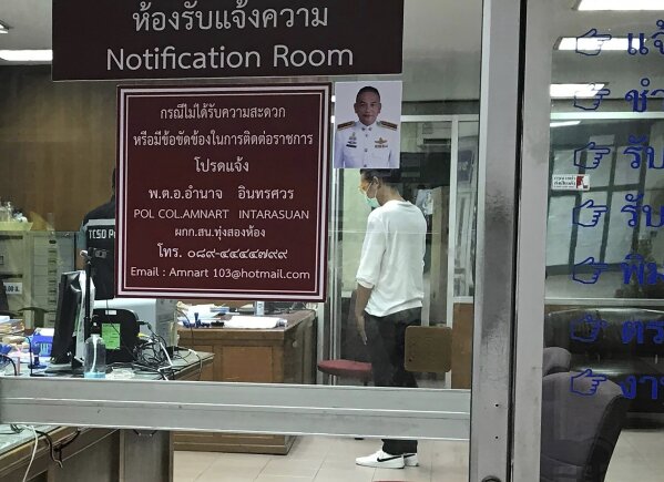 In this March 24, 2020, photo released by the Thai Lawyers for Human Rights, Danai Ussama stands inside a police station in Bangkok, while he is processed after being arrested for posting a message on social media criticizing the lack of government measures in screening passengers when arriving at the airport. As governments across the world enact emergency measures to keep people at home and stave off the pandemic, some are unhappy about having their missteps publicized. Others are taking advantage of the crisis to silence critics and tighten control. (Thai Lawyers for Human Rights via AP)