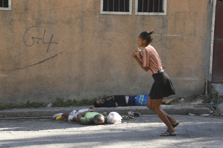A woman walks past bodies of two men killed by unknown assailants in Port-au-Prince, Haiti, Sunday, March 3, 2024. (AP Photo/Odelyn Joseph)