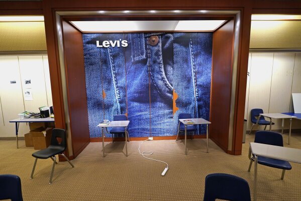 A large Levi's jeans display highlights the center of an empty classroom, built in a former department store, at Downtown Burlington High School, Monday, March 22, 2021, in Burlington, Vt. Students who once shopped at a downtown mall are now attending high school in the mall's former Macy's store, taking escalators to and from classes. The existing Burlington High School was closed last August after PCBs were found in the building. (AP Photo/Charles Krupa)