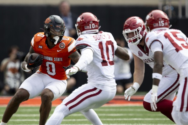 Oklahoma State running back Ollie Gordon II (0) runs into Arkansas linebacker Xavian Sorey Jr. (10) and others in the first half of an NCAA college football game Saturday, Sept. 7, 2024, in Stillwater, Okla. (AP Photo/Mitch Alcala)