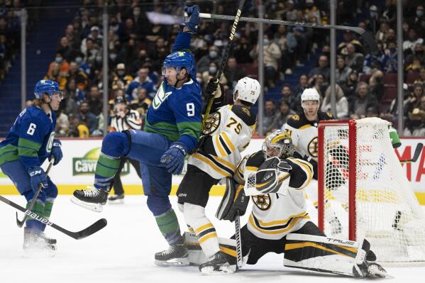 Boston Bruins defenseman Connor Clifton (75) tries to clear Vancouver Canucks center J.T. Miller (9) from in front of Bruins goaltender Jeremy Swayman (1) during the second period of an NHL hockey game Wednesday, Dec. 8, 2021 in Vancouver, British, Columbia.  (Jonathan Hayward/The Canadian Press via AP)