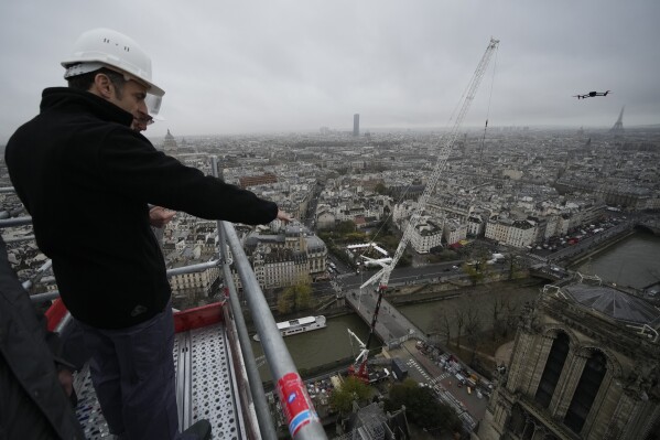 French President Emmanuel Macron watches Notre Dame cathedral from the top of the spire of the monument Friday, Dec. 8, 2023 in Paris. French President Emmanuel Macron is visiting Notre Dame Cathedral on Friday, marking the one-year countdown to its reopening in 2024 following extensive restoration after the fire four years ago. (AP Photo/Christophe Ena, Pool)