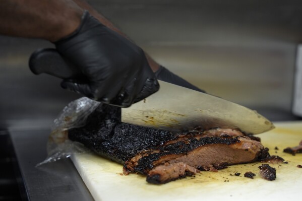 A line cook slices beef brisket, Wednesday, June 12, 2024, at a barbecue restaurant in Cincinnati. Psychologists have known for years now that men tend to eat more meat than women, but a study of people around the world now reveals that that's true across cultures. (AP Photo/Joshua A. Bickel)