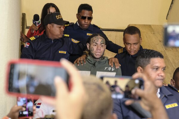 Rapper Daniel Hernandez, known as Tekashi 6ix9ine, is escorted by police as he arrives to appear at court, Palace of Justice, in Santo Domingo, Dominican Republic, Thursday, Jan. 25, 2024. Authorities arrested the rapper on Jan. 17 on charges of domestic violence. (AP Photo/Ricardo Hernandez)