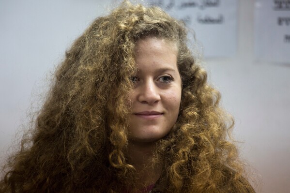 FILE - In this Feb. 13, 2018 file photo, Palestinian activist Ahed Tamimi stands inside the Ofer military prison near Jerusalem. Israeli authorities arrested Tamimi this week for online speech that her family insists wasn't hers. Israeli authorities say that Tamimi is suspected of incitement to terrorism for an Instagram post under her account. (AP Photo/Ariel Schalit, File)