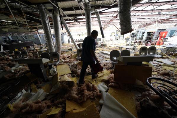 In the aftermath of Hurricane Ida, Dewayne Pellegrin a bowling alley mechanic, cleans up the heavily damaged Bowl South of Louisiana Tuesday, Aug. 31, 2021, in Houma, La. (AP Photo/David J. Phillip)