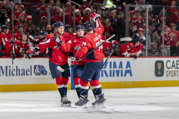 Washington Capitals center Hendrix Lapierre (29) celebrates with defenseman Martin Fehervary (42) and defenseman John Carlson (74) after Lapierre scored against the New York Islanders during the first period of an NHL hockey game Wednesday, Dec. 20, 2023, in Washington. (AP Photo/Stephanie Scarbrough)