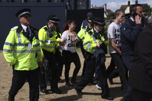 Just Stop Oil protesters are led away by police and security near the 17th hole during the second day of the British Open Golf Championships at the Royal Liverpool Golf Club in Hoylake, England, Friday, July 21, 2023. (AP Photo/Peter Morrison)