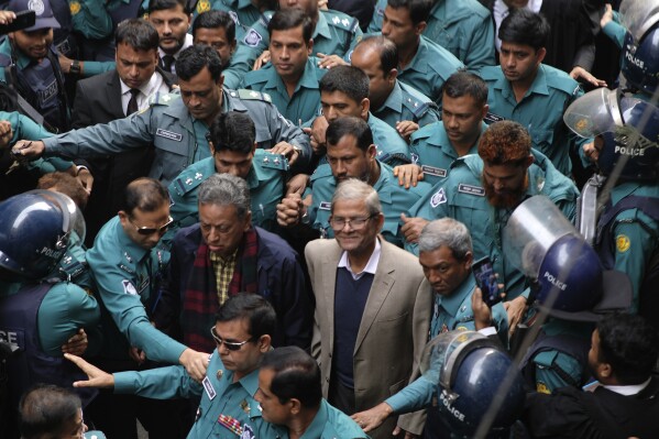 Bangladesh Nationalist Party or BNP Secretary General Mirza Fakhrul Islam Alamgir and Standing Committee Member Amir Khasru Mahmud Chowdhury, white hair, surrounded by policemen arrive at the Chief Metropolitan Magistrate Court in Dhaka, Bangladesh, Monday, Dec.18, 2023. A Dhaka court on Monday denied BNP leaders Mirza Fakhrul Islam Alamgir and Amir Khasru Mahmud Chowdhury bail in a case filed at Paltan police station for sabotage. (AP Photo/ Mahmud Hossain Opu)