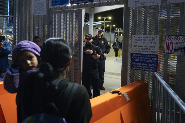 FILE - Paola, front, from Guatemala, holds her daughter as she asks U.S. Customs and Border Protection officials about new asylum rules at the San Ysidro Port of Entry on May 11, 2023, in Tijuana, Mexico.  Prominent Latino Democrats in Congress have been monitoring the progress of negotiations on border security and asylum restrictions, and have tried to raise concerns about the direction of the talks, heard first with quiet warnings and now with open opposition.  (AP Photo/Gregory Paul, File)