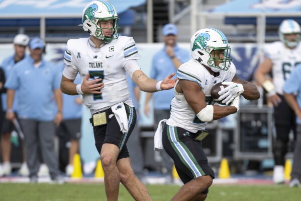 Tulane quarterback Michael Pratt (7) hands off the ball to Tulane running back Makhi Hughes (21) during the second half an NCAA football game against Florida Atlantic on Saturday, Nov. 18, 2023 in Boca Raton, Fla. (AP Photo/Doug Murray)