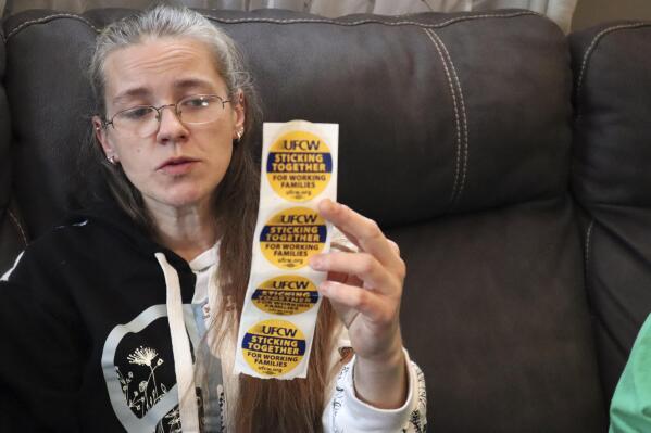 Former Tudor's Biscuit World employee Jennifer Patton, 38, holds up stickers displaying the logo of the United Food & Commercial Workers Local 400 union at her coworker's home in Elkview, W.Va., on Jan. 20, 2022. Patton said she was retaliated against and fired by management after she joined efforts to unionize the restaurant. Employees at the Elkview, W.Va., restaurant have already case ballots to decide whether or not they want to create a union. The votes will be read Tuesday. (AP Photo/Leah M. Willingham)