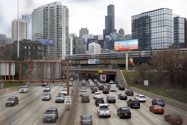 FILE - Traffic flows along Interstate 90 highway as a Metra suburban commuter train moves along an elevated track in Chicago on March 31, 2021.   With upcoming data showing traffic deaths soaring, the Biden administration is steering $5 billion in federal aid to cities and localities to address the growing crisis by slowing down cars, carving out bike paths and wider sidewalks, and nudging commuters to public transit.  (AP Photo/Shafkat Anowar, File)