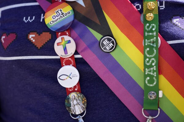 FILE - A representative of Dignity USA, a group of LGBTQ+ Catholics, wears pins on the lanyard of his pilgrim credential, outside the Sao Vicente de Paulo Parish Social Center, after Pope Francis visited it, in the Serafina neighbourhood of Lisbon, Friday, Aug. 4, 2023. (AP Photo/Armando Franca, File)