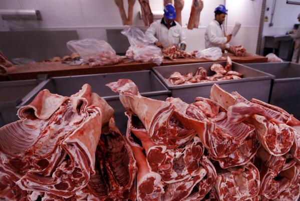 FILE - Butchers prepare cuts of meat at Smithfield Market on July 18, 2016, in London. Greenhouse gas emissions from the way humans consume food could add nearly one degree of warming to the Earth’s climate by 2100, according to a new study Monday, March 6, 2023. Researchers found that the majority of greenhouse gas emissions come from three major food groups — meat from animals like cows, sheep and goats, dairy and rice. (AP Photo/Kirsty Wigglesworth, File)