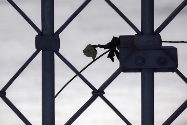 A rose hangs at the closed camp entrance at the 75th anniversary of the liberation of the former Nazi concentration camp Buchenwald by the US Army near Weimar, Germany, Saturday, April 11, 2020. Because of Corona crisis, the memorial is currently closed and all commemoration ceremonies with survivors have been cancelled. For most people, the new coronavirus causes only mild or moderate symptoms, such as fever and cough. For some, especially older adults and people with existing health problems, it can cause more severe illness, including pneumonia. (AP Photo/Jens Meyer)