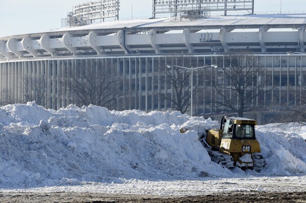 A vehicle pushes up pikes of snow after trucks dump their loads of snow in the parking lots of RFK Stadium in Washington, Monday, Jan. 25, 2016. (AP Photo/Susan Walsh, File)