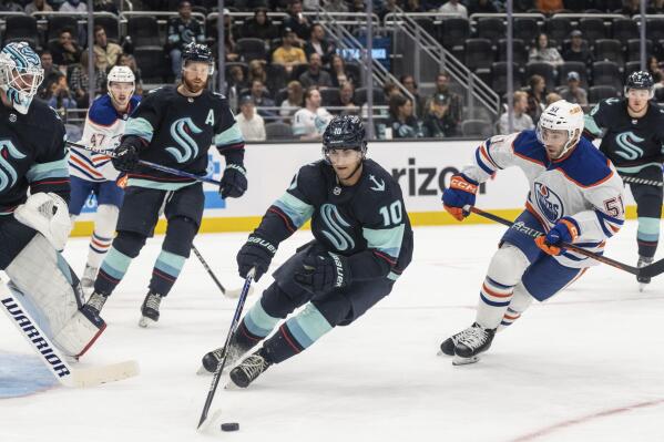 Seattle Kraken forward Matty Beniers, center, skates against Edmonton Oilers forward Luke Esposito during the second period of a preseason NHL hockey game, Monday, Sept. 26, 2022, in Seattle. (AP Photo/Stephen Brashear)