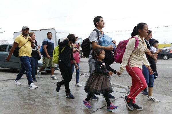 
              Migrants walk along a highway as a new caravan of several hundred people sets off in hopes of reaching the distant United States, in San Pedro Sula, Honduras, shortly after dawn Wednesday, April 10, 2019. Parents who gathered at the bus station with their children to join the caravan say they can't support their families with what they can earn in Honduras and are seeking better opportunities. (AP Photo/Delmer Martinez)
            