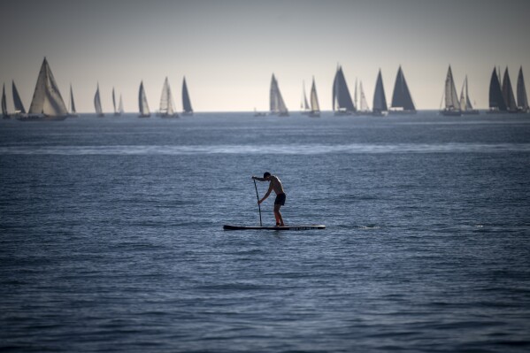 FILE - A man paddles in the Mediterranean Sea in Barcelona, Spain, Feb. 4, 2024. Earth has exceeded global heat records in February, according to the European Union climate agency Copernicus. (AP Photo/Emilio Morenatti, File)