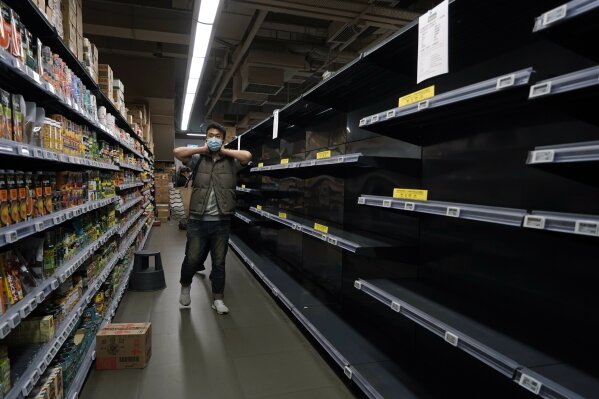 A man wearing face mask, walks past empty shelves at a supermarket in Hong Kong, Thursday, Feb. 13, 2020. China on Thursday reported 254 new deaths and a spike in virus cases of 15,152, after the hardest-hit province of Hubei applied a new classification system that broadens the scope of diagnoses for the outbreak, which has spread to more than 20 countries. (AP Photo/Kin Cheung)