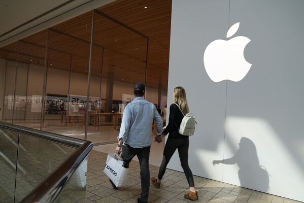People walk by an Apple store on Friday, Oct. 20, 2023, in Denver. Apple reports earnings on Thursday, Nov. 2, 2023. (AP Photo/Brittany Peterson)