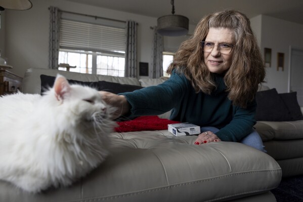 Donna Cooper pets her cat Cade at her home in Front Royal, Va., on Friday, March 1, 2024. Cooper has heard that people gain back weight when they stop using drugs like Wegovy, but she hopes to be an exception. She's on her last box of Wegovy injections. Once she's done, Cooper said she’ll just continue with a strict diet and exercise plan. (AP Photo/Amanda Andrade-Rhoades)