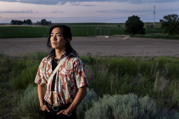 Jonnie Narita, 24, whose grandfather George Nakagawa was a baseball star at the camp, poses for a portrait in front of a recreated baseball diamond at Minidoka National Historic Site, Saturday, July 6, 2023, in Jerome, Idaho. It wasn't until after Nakagawa's family convinced him to attend the celebration of the reconstructed diamond in 2016 that he began to share more of his incarceration experience. "Without [this] place we wouldn't have all these family stories from my grandpa," said Narita. (AP Photo/Lindsey Wasson)
