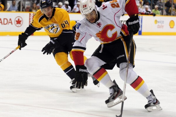 FILE - Calgary Flames center Akim Aliu (29) controls the puck against Nashville Predators defenseman Victor Bartley (64) during the first period of an NHL hockey game April 23, 2013, in Nashville, Tenn. After years of feeling alienated by the NHL and campaigning to diversify the sport, Akim Aliu is getting one more shot at playing pro hockey, this time with the San Jose Sharks minor-league affiliate. Sharks general manager Mike Grier informed reporters at the league’s GM meetings in Florida on Wednesday, March 20, 2024, that he offered Aliu a tryout contract with the American Hockey League San Jose Barracuda for the remainder of the season. (AP Photo/Mike Strasinger, File)