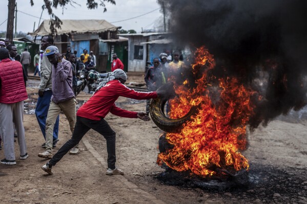 A protester burns tyres to block the road in the Kibera neighborhood of Nairobi, Kenya, Wednesday, July 12, 2023. Anti-government protesters are demonstrating in a number of Kenyan cities against newly imposed taxes and the cost of living. (AP Photo/Samson Otieno)