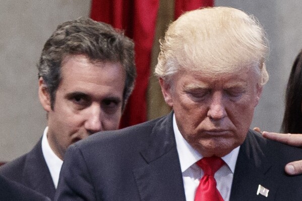 FILE - People lay hands in prayer on Republican presidential candidate Donald Trump, right, as attorney Michael Cohen looks on during a visit to the Pastors Leadership Conference at New Spirit Revival Center, Sept. 21, 2016, in Cleveland. Cohen is prosecutors’ most central witness in former President Trump's hush money trial. But Trump’s fixer-turned-foe is also as challenging a star witness as they come. The now-disbarred lawyer has a tortured history with Trump. (AP Photo/ Evan Vucci, File)