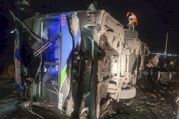 In this handout photo provided by the Peru's Highway Police, rescue workers attend to a bus that collided with a cargo train in La Oroya, Peru, Sunday, May 26, 2024. (Peru's Highway Police, via AP)