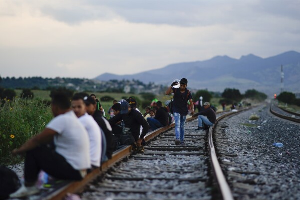 Migrants wait along a rail line hoping to board a freight train heading north, in Huehuetoca, Mexico, Sept. 19, 2023. Ferromex, Mexico's largest railroad company announced that it was suspending operations of its cargo trains due to the massive number of migrants that are illegally hitching a ride on its trains moving north towards the U.S. border. (AP Photo/Eduardo Verdugo)
